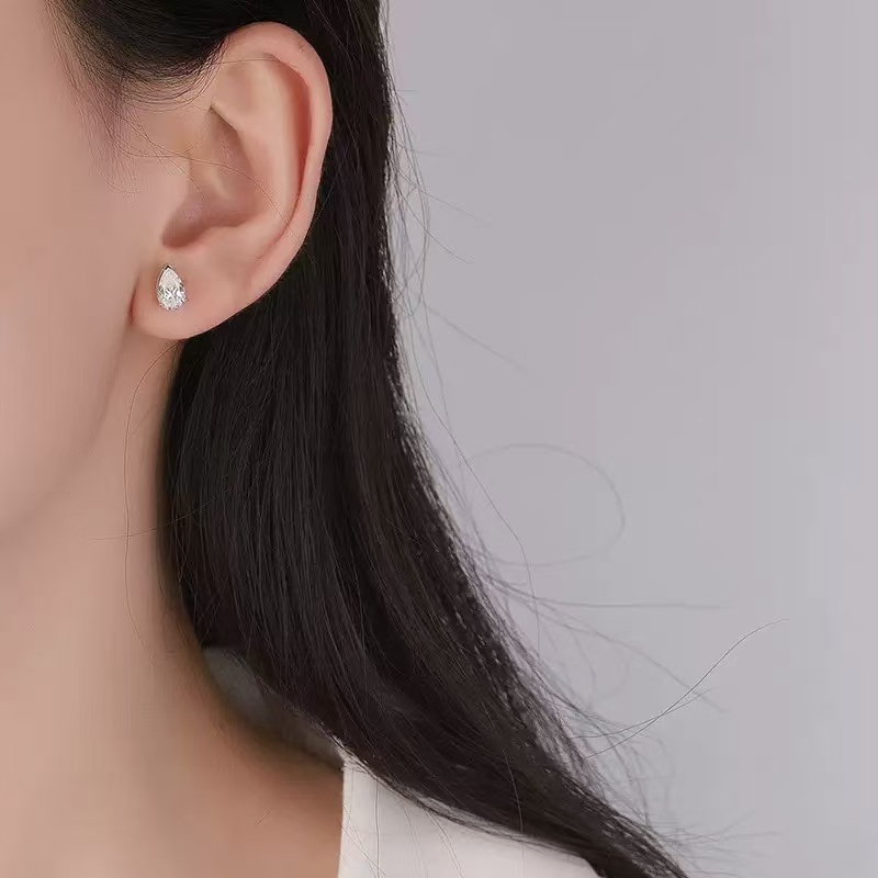 Woman wearing minimalist pear cut moissanite stud earrings